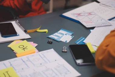 Uxui tasarımcılarından oluşan bir ekip bilgisayar ekranını işaret ederek ofiste yeni mobil uygulama tasarımını tartışıyor.