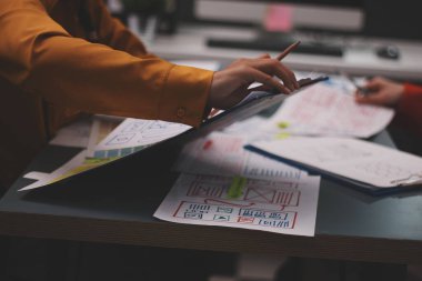 Uxui tasarımcılarından oluşan bir ekip bilgisayar ekranını işaret ederek ofiste yeni mobil uygulama tasarımını tartışıyor.