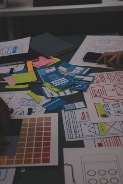 Uxui tasarımcılarından oluşan bir ekip bilgisayar ekranını işaret ederek ofiste yeni mobil uygulama tasarımını tartışıyor.