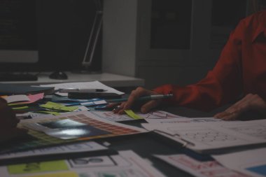 Uxui tasarımcılarından oluşan bir ekip bilgisayar ekranını işaret ederek ofiste yeni mobil uygulama tasarımını tartışıyor.