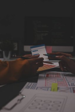 Uxui tasarımcılarından oluşan bir ekip bilgisayar ekranını işaret ederek ofiste yeni mobil uygulama tasarımını tartışıyor.