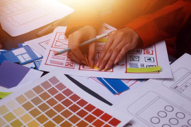 Uxui tasarımcılarından oluşan bir ekip bilgisayar ekranını işaret ederek ofiste yeni mobil uygulama tasarımını tartışıyor.