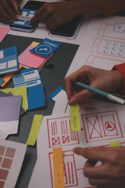 Uxui tasarımcılarından oluşan bir ekip bilgisayar ekranını işaret ederek ofiste yeni mobil uygulama tasarımını tartışıyor.