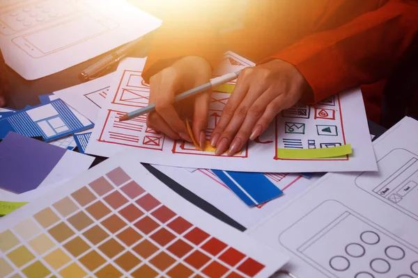 Uxui tasarımcılarından oluşan bir ekip bilgisayar ekranını işaret ederek ofiste yeni mobil uygulama tasarımını tartışıyor.