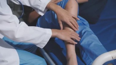 Asyalı fizyoterapist yaşlı bir kadının bacaklarını iyileştirmek için fizik tedavi uyguluyor..