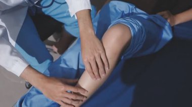 Asyalı fizyoterapist yaşlı bir kadının bacaklarını iyileştirmek için fizik tedavi uyguluyor..