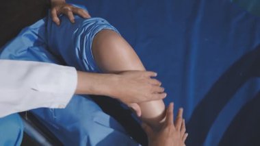 Asyalı fizyoterapist yaşlı bir kadının bacaklarını iyileştirmek için fizik tedavi uyguluyor..