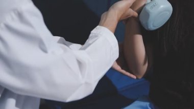 Asyalı fizyoterapist yaşlı bir kadının bacaklarını iyileştirmek için fizik tedavi uyguluyor..