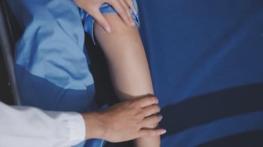 Asyalı fizyoterapist yaşlı bir kadının bacaklarını iyileştirmek için fizik tedavi uyguluyor..