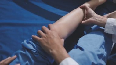 Asyalı fizyoterapist yaşlı bir kadının bacaklarını iyileştirmek için fizik tedavi uyguluyor..