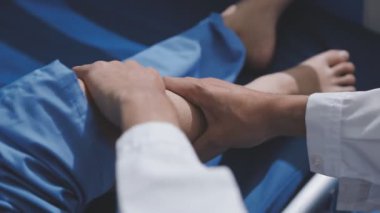 Asyalı fizyoterapist yaşlı bir kadının bacaklarını iyileştirmek için fizik tedavi uyguluyor..