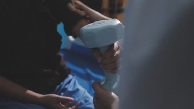 Evde dambıl kullanarak fizyoterapist eğitimi alan yaşlı bir kadın. Terapist, huzurevi egzersizlerinde yaşlı kadına yardım ediyor. Yaşlı bir hasta kollarını uzatmış halterler kullanıyor..