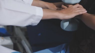 Evde dambıl kullanarak fizyoterapist eğitimi alan yaşlı bir kadın. Terapist, huzurevi egzersizlerinde yaşlı kadına yardım ediyor. Yaşlı bir hasta kollarını uzatmış halterler kullanıyor..