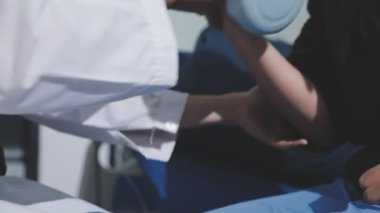 Evde dambıl kullanarak fizyoterapist eğitimi alan yaşlı bir kadın. Terapist, huzurevi egzersizlerinde yaşlı kadına yardım ediyor. Yaşlı bir hasta kollarını uzatmış halterler kullanıyor..