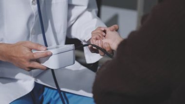 Teste gir, elinden geleni yap. Evde tansiyon ölçer ile yaşlı bir kadını muayene eden bir doktorun fotoğrafı..