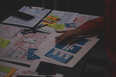 Uxui tasarımcılarından oluşan bir ekip bilgisayar ekranını işaret ederek ofiste yeni mobil uygulama tasarımını tartışıyor.