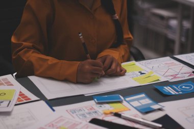 Uxui tasarımcılarından oluşan bir ekip bilgisayar ekranını işaret ederek ofiste yeni mobil uygulama tasarımını tartışıyor.