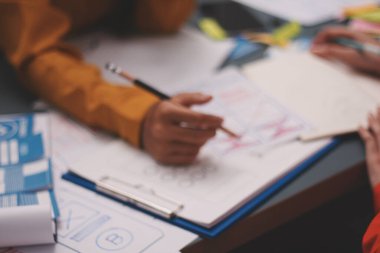 Uxui tasarımcılarından oluşan bir ekip bilgisayar ekranını işaret ederek ofiste yeni mobil uygulama tasarımını tartışıyor.