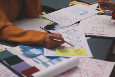 Uxui tasarımcılarından oluşan bir ekip bilgisayar ekranını işaret ederek ofiste yeni mobil uygulama tasarımını tartışıyor.