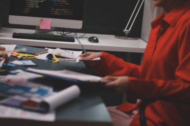 Uxui tasarımcılarından oluşan bir ekip bilgisayar ekranını işaret ederek ofiste yeni mobil uygulama tasarımını tartışıyor.