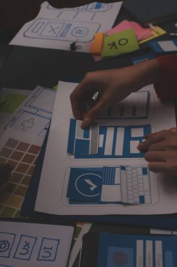 Uxui tasarımcılarından oluşan bir ekip bilgisayar ekranını işaret ederek ofiste yeni mobil uygulama tasarımını tartışıyor.