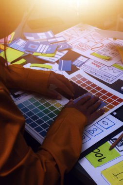 Uxui tasarımcılarından oluşan bir ekip bilgisayar ekranını işaret ederek ofiste yeni mobil uygulama tasarımını tartışıyor.