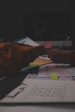 Uxui tasarımcılarından oluşan bir ekip bilgisayar ekranını işaret ederek ofiste yeni mobil uygulama tasarımını tartışıyor.