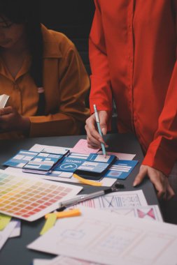 Uxui tasarımcılarından oluşan bir ekip bilgisayar ekranını işaret ederek ofiste yeni mobil uygulama tasarımını tartışıyor.