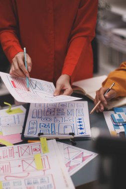 Uxui tasarımcılarından oluşan bir ekip bilgisayar ekranını işaret ederek ofiste yeni mobil uygulama tasarımını tartışıyor.