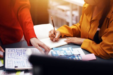 Uxui tasarımcılarından oluşan bir ekip bilgisayar ekranını işaret ederek ofiste yeni mobil uygulama tasarımını tartışıyor.