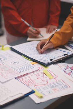 Uxui tasarımcılarından oluşan bir ekip bilgisayar ekranını işaret ederek ofiste yeni mobil uygulama tasarımını tartışıyor.