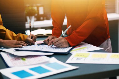 Uxui tasarımcılarından oluşan bir ekip bilgisayar ekranını işaret ederek ofiste yeni mobil uygulama tasarımını tartışıyor.