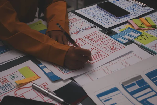 Uxui tasarımcılarından oluşan bir ekip bilgisayar ekranını işaret ederek ofiste yeni mobil uygulama tasarımını tartışıyor.