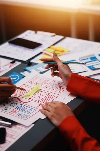 Uxui tasarımcılarından oluşan bir ekip bilgisayar ekranını işaret ederek ofiste yeni mobil uygulama tasarımını tartışıyor.