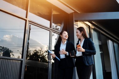 İş adamları modern ofisin önünde yürür ve birbirleriyle konuşurlar.