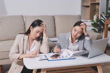 İki iş kadını ofiste dizüstü bilgisayarla çalışırken stresli hissediyorlar