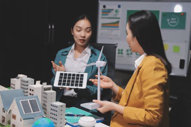 İki iş adamı ekibi güneş pili ve rüzgar türbini jeneratörü ile sürdürülebilir ve yenilenebilir temiz enerji ürünü, CO2 emisyonları küresel ısınma projesini planlıyor ve tartışıyor.