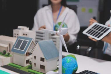 Güneş panelleri ve yeşil ev modeli tutan genç kadın mühendis..