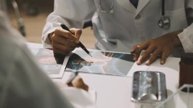 Medical team meeting analyzing blood test results in hospital laboratory. Doctors and scientists in lab coats are having a discussion about blood test result, holding test tubes and taking notes.