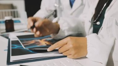 Medical team meeting analyzing blood test results in hospital laboratory. Doctors and scientists in lab coats are having a discussion about blood test result, holding test tubes and taking notes.