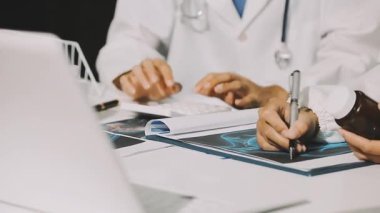 Medical team meeting analyzing blood test results in hospital laboratory. Doctors and scientists in lab coats are having a discussion about blood test result, holding test tubes and taking notes.