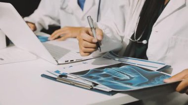 Medical team meeting analyzing blood test results in hospital laboratory. Doctors and scientists in lab coats are having a discussion about blood test result, holding test tubes and taking notes.