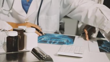 Medical team meeting analyzing blood test results in hospital laboratory. Doctors and scientists in lab coats are having a discussion about blood test result, holding test tubes and taking notes.