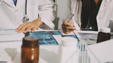 Medical team meeting analyzing blood test results in hospital laboratory. Doctors and scientists in lab coats are having a discussion about blood test result, holding test tubes and taking notes.