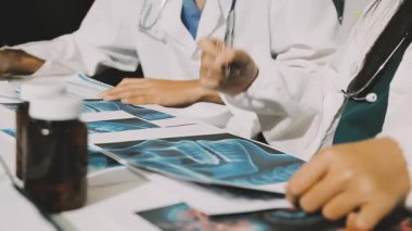 Medical team meeting analyzing blood test results in hospital laboratory. Doctors and scientists in lab coats are having a discussion about blood test result, holding test tubes and taking notes.