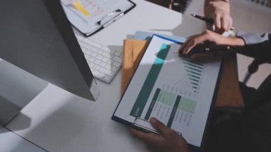 Ofiste çalışan denetçi ve muhasebeci ekibi mali verileri ve muhasebe kayıtlarını hesap makinesiyle analiz ediyor. Muhasebe şirketi kârlı nakit akışı için finansman ve vergilendirme planlaması sağlıyor