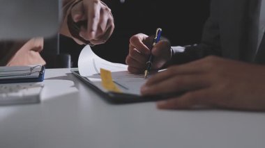 Ofiste çalışan denetçi ve muhasebeci ekibi mali verileri ve muhasebe kayıtlarını hesap makinesiyle analiz ediyor. Muhasebe şirketi kârlı nakit akışı için finansman ve vergilendirme planlaması sağlıyor