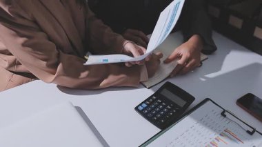 Ofiste çalışan denetçi ve muhasebeci ekibi mali verileri ve muhasebe kayıtlarını hesap makinesiyle analiz ediyor. Muhasebe şirketi kârlı nakit akışı için finansman ve vergilendirme planlaması sağlıyor