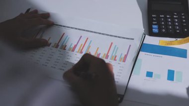 Ofiste çalışan denetçi ve muhasebeci ekibi mali verileri ve muhasebe kayıtlarını hesap makinesiyle analiz ediyor. Muhasebe şirketi kârlı nakit akışı için finansman ve vergilendirme planlaması sağlıyor