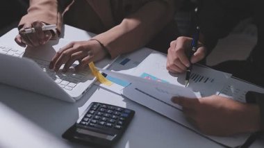 Ofiste çalışan denetçi ve muhasebeci ekibi mali verileri ve muhasebe kayıtlarını hesap makinesiyle analiz ediyor. Muhasebe şirketi kârlı nakit akışı için finansman ve vergilendirme planlaması sağlıyor